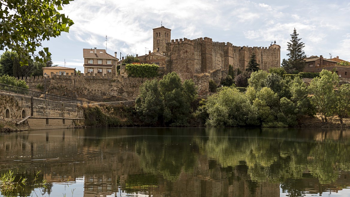 Vista del conjunto medieval de Buitrago del Lozoya en el que puede apreciarse la muralla y el castillo entre la vegetación.
