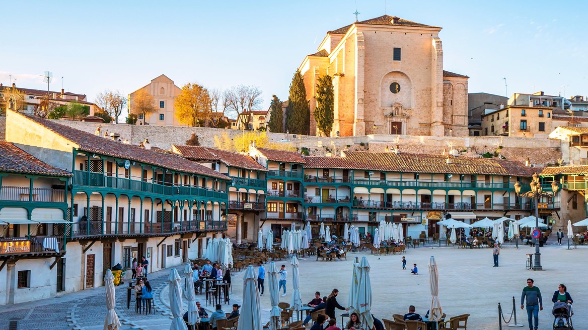 The Plaza Mayor of Chinchón highlights its popular Castilian architecture in a sunset brimming with life.