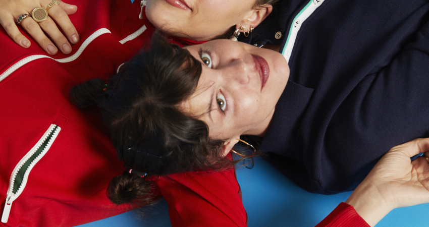 Hinds interview. Ana and Carlotta look at the camera while resting their heads in each other's shoulders.