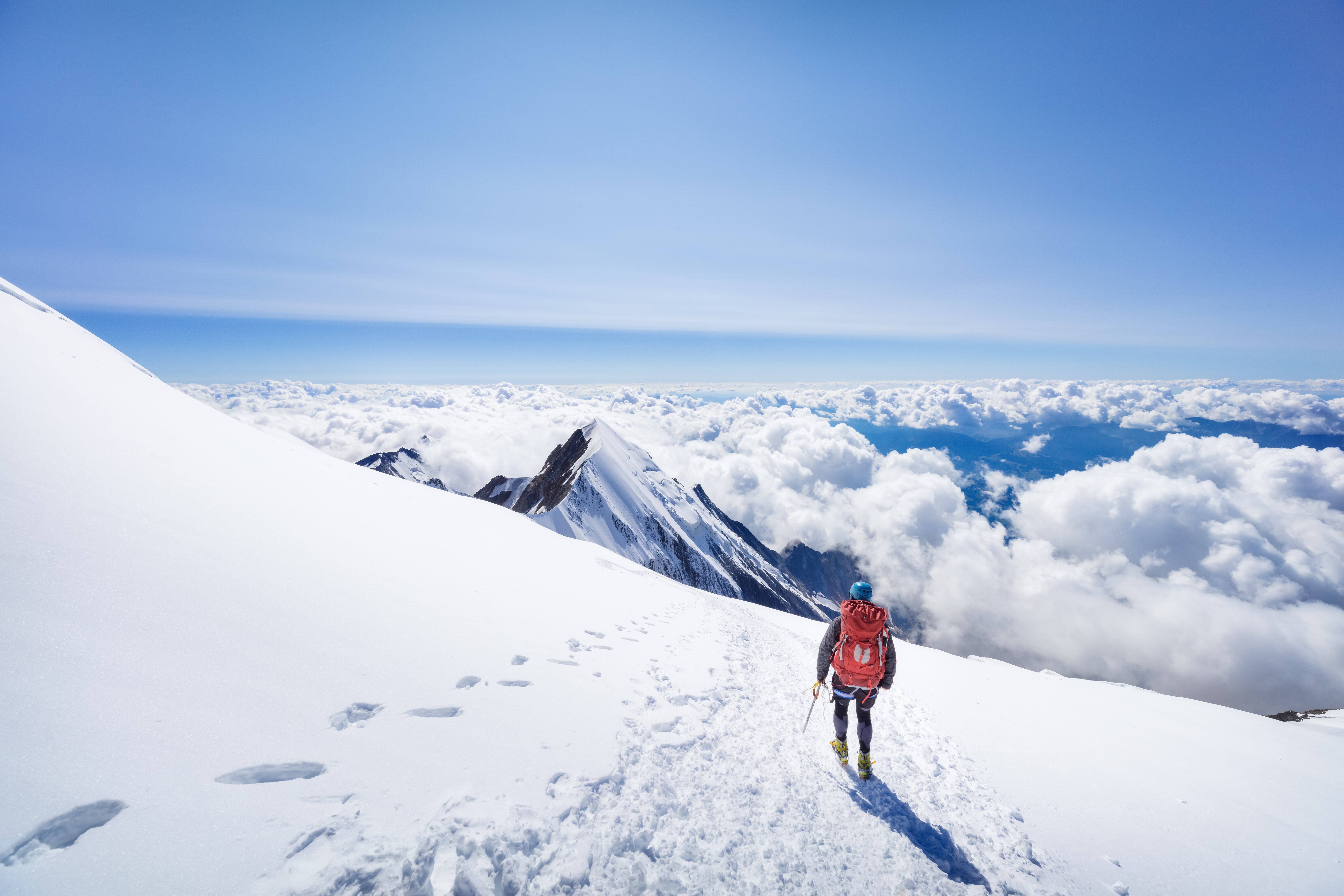 Viaja a Ginebra por 9000 Avios. En la imagen, un alpinista contempla los Alpes desde una de las cimas más altas, rodeado por nubes