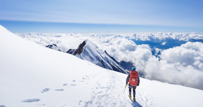 Viaja a Ginebra por 9000 Avios. En la imagen, un alpinista contempla los Alpes desde una de las cimas más altas, rodeado por nubes