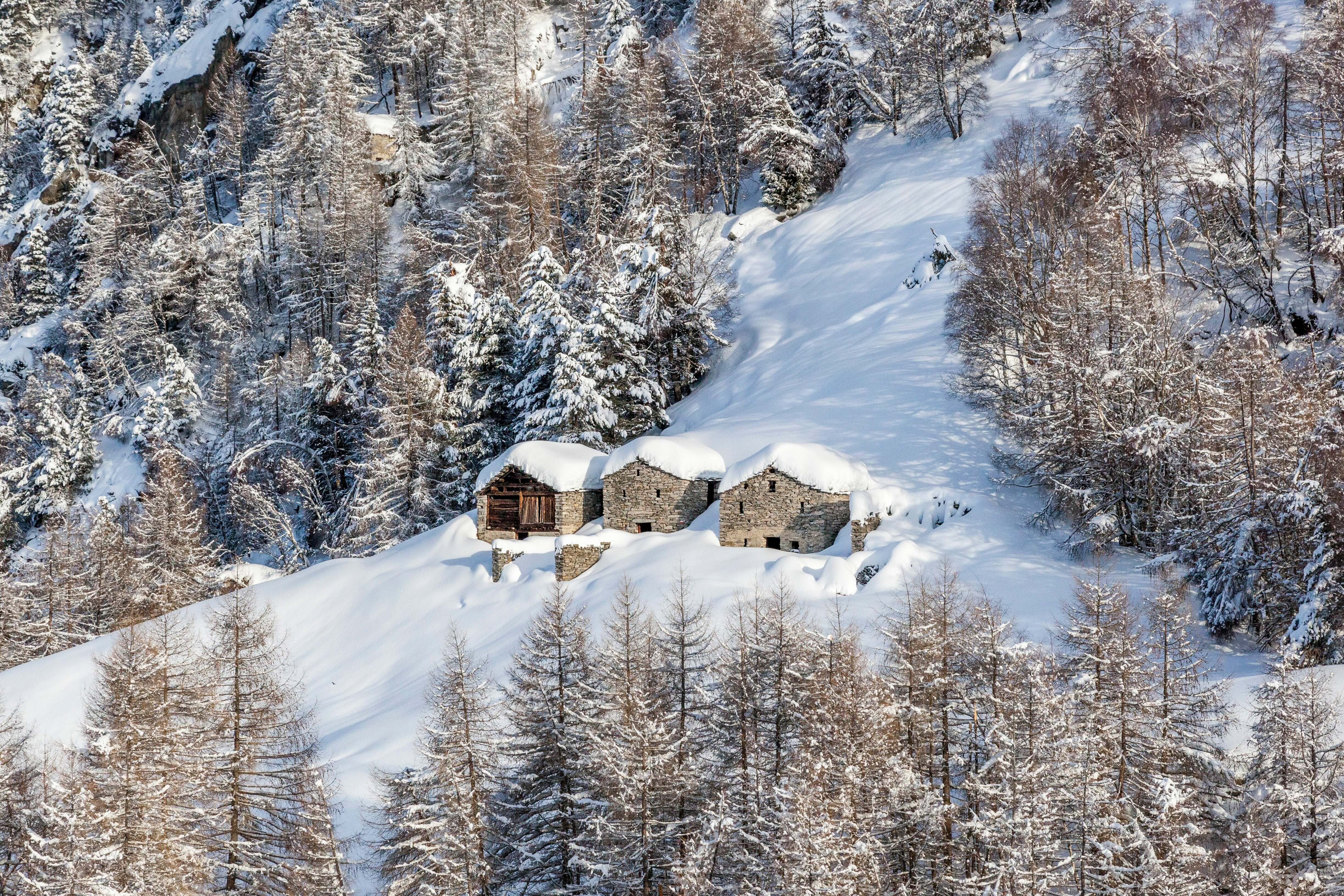 Travel to Milan for 18 750 Avios. In the picture, three wood and stone huts sit on the snowy slope of one of the mountains where you can ski downhill.
