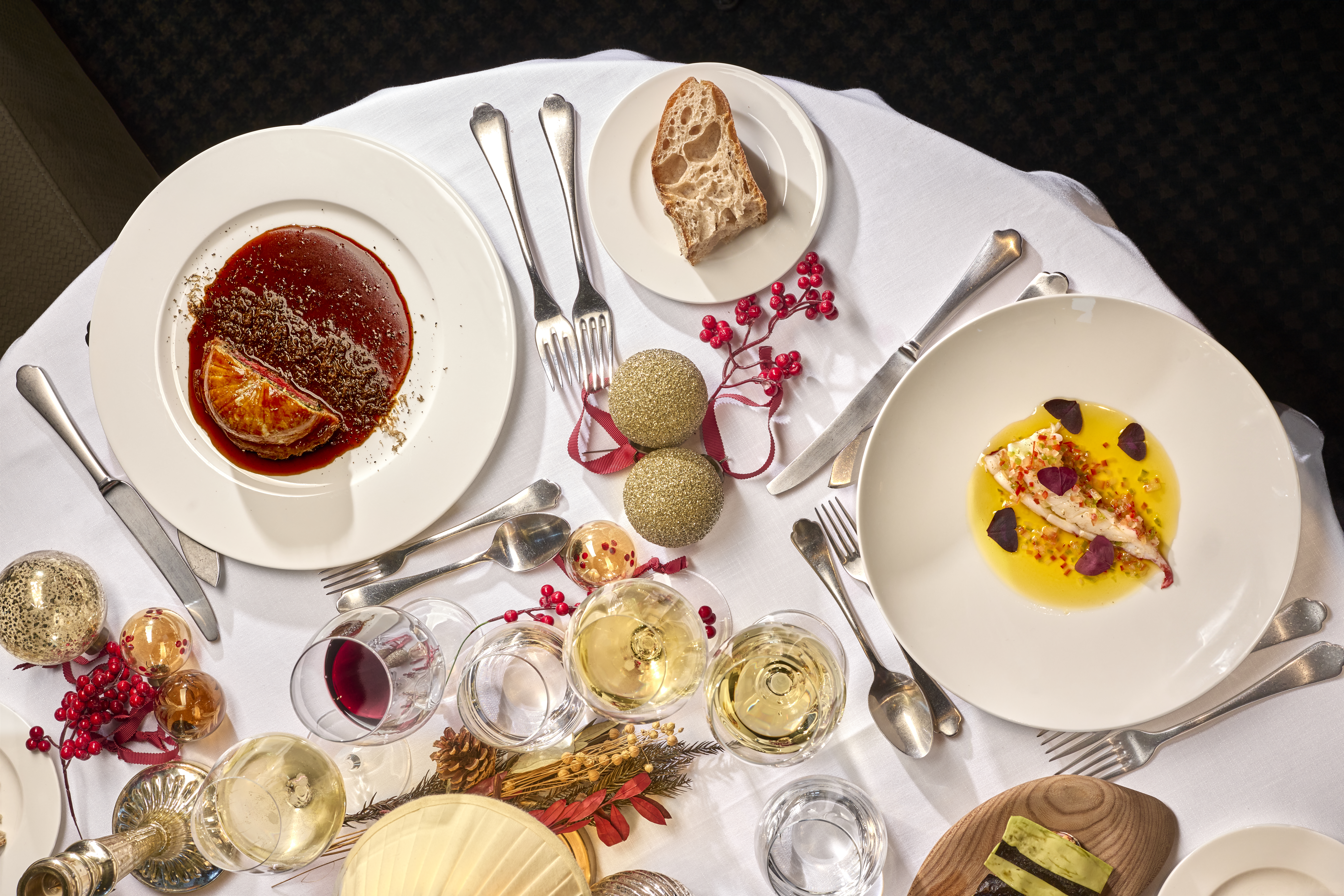 Vista de la mesa navideña del Cñub Financiero, con dos de sus platos principales acompañados con copas de diferentes vinos y decoración navideña