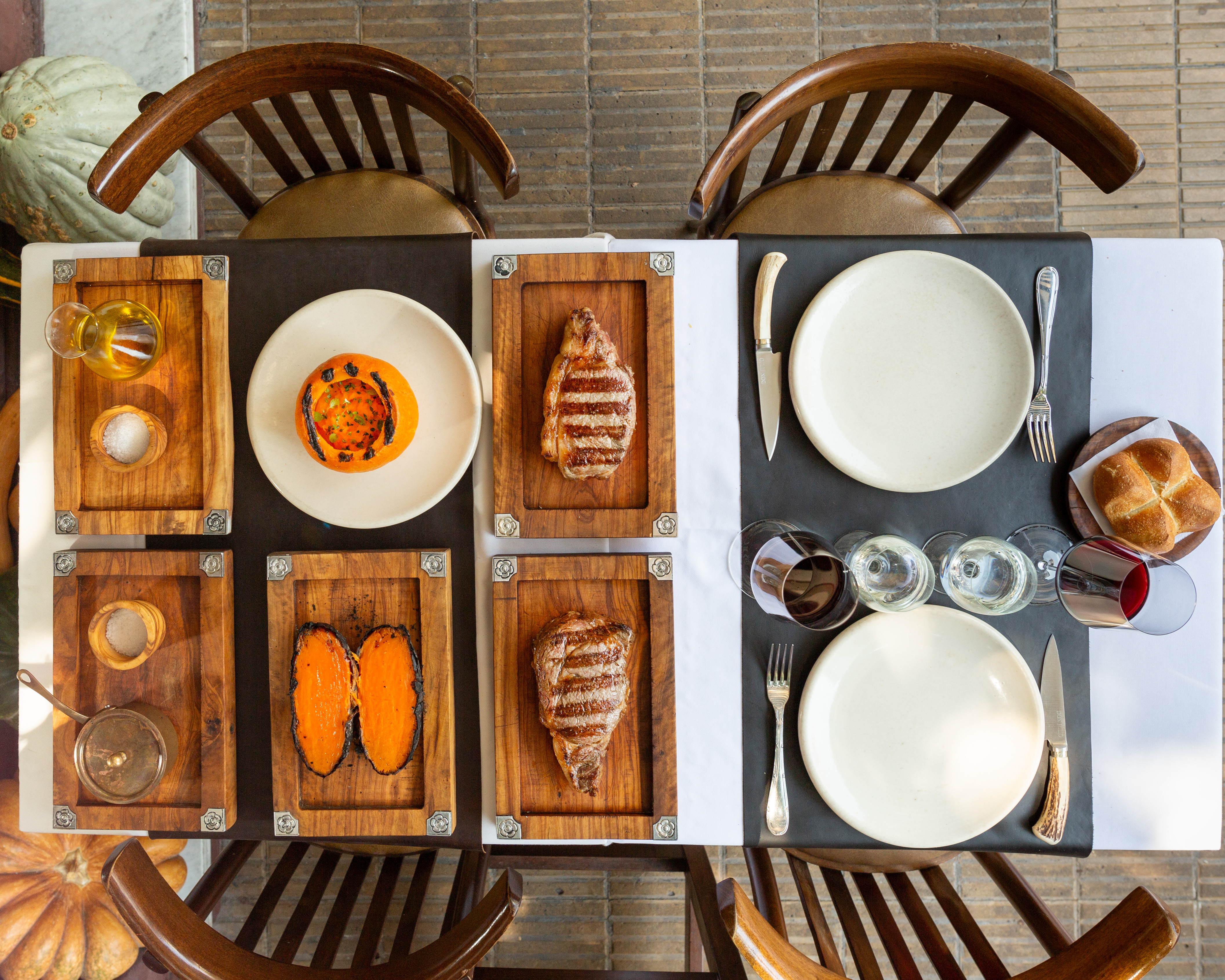 Overhead view of a table at Don Julio, with wines, meats and roasted sweet potato, as well as soup and bread accompaniments