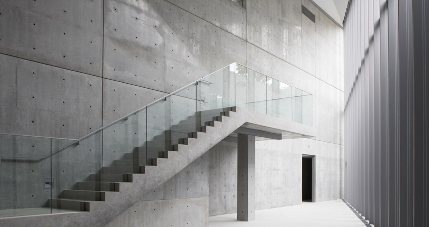 En la imagen, vértice interior en el que se encuentran las dos paredes exteriores del edificio, en cemento, acero y vidrio. También puede observarse un tramo de escaleras que no lleva a ninguna parte y una puerta que da acceso a una estancia misteriosa