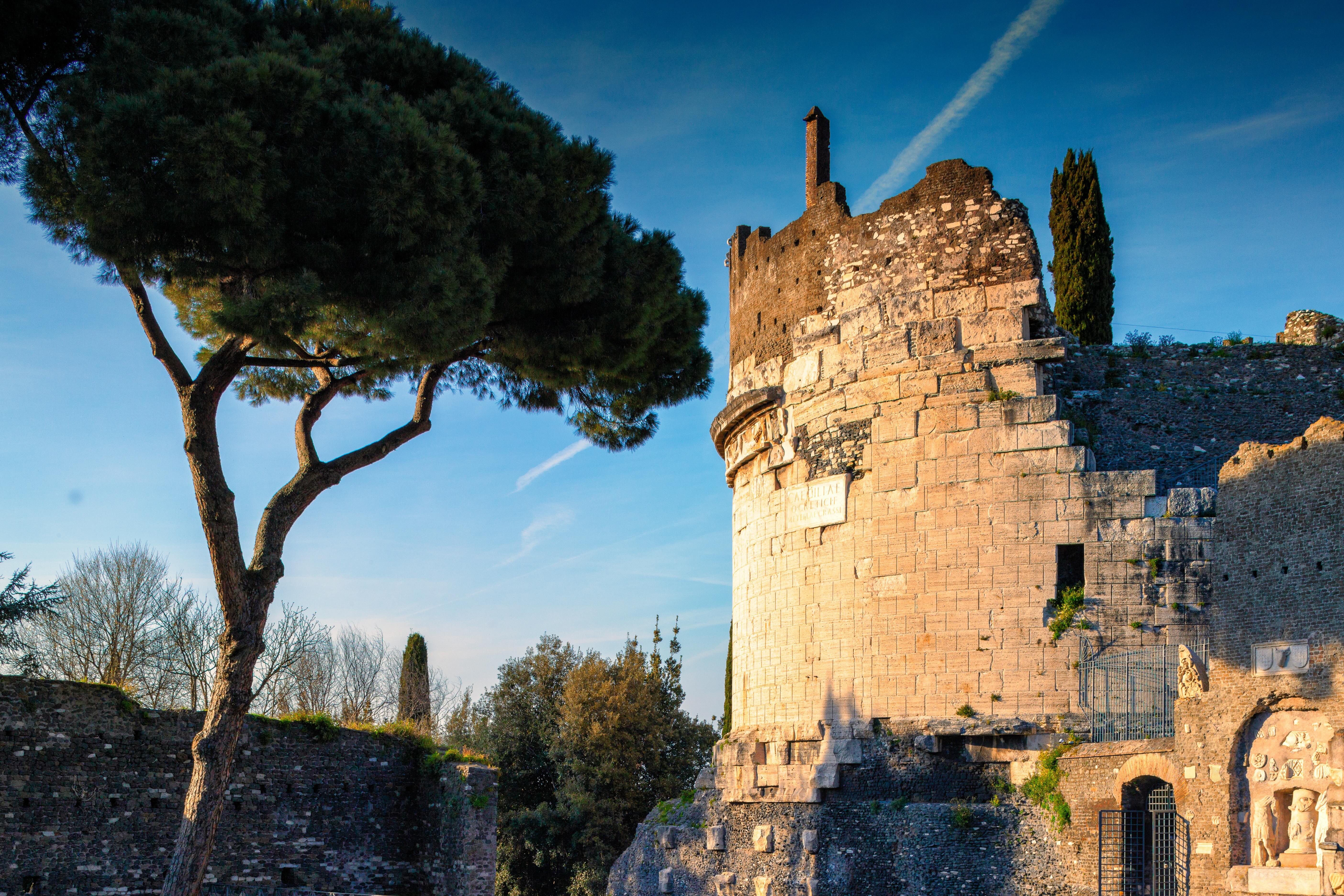 The Mausoleum of Cecilia Metella at sunset, with the circular structure and remains of the medieval wall, surrounded by trees