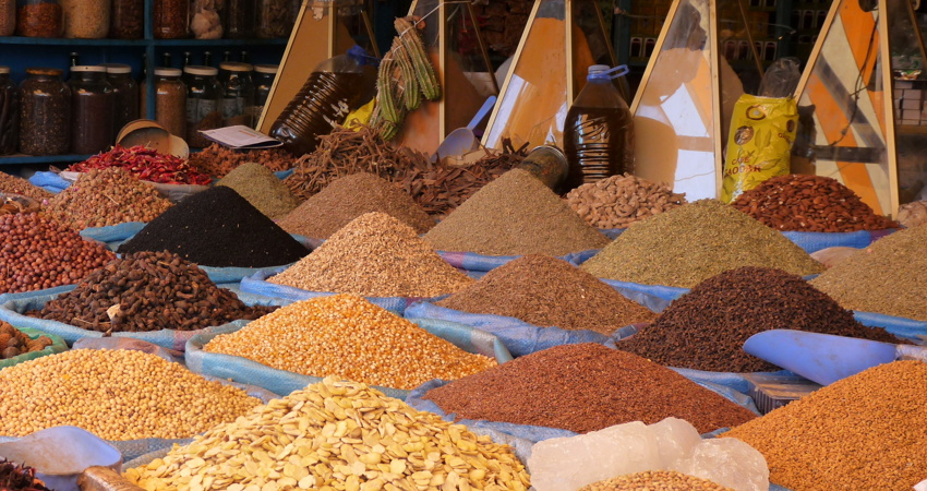 The picture shows a spice stall in the Central Market, with different types of products in piles in sky-blue containers or in glass pyramid dispensers.