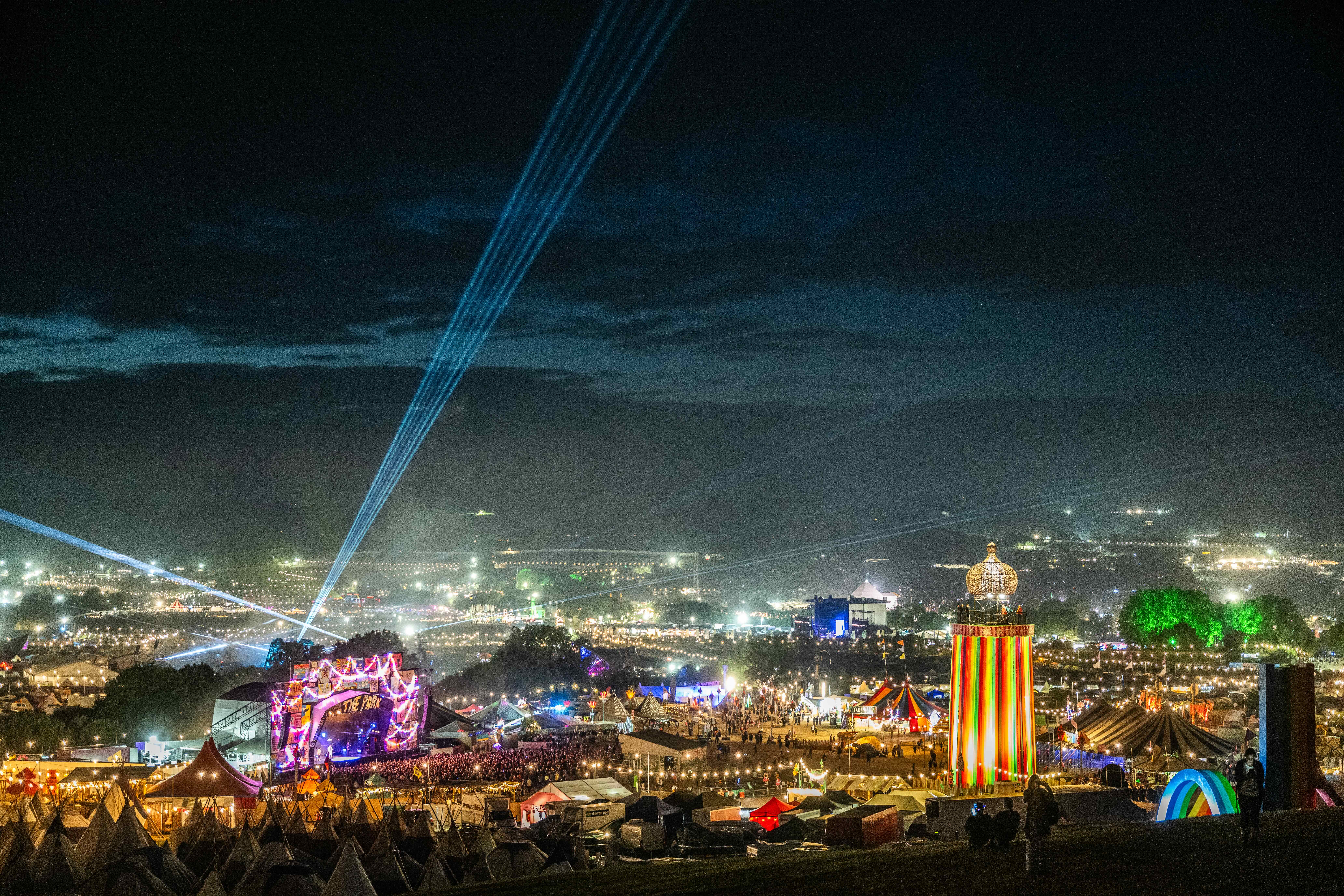 The picture shows a sea of lights, a colourful lighthouse and a huge stage surrounded by countless tents.