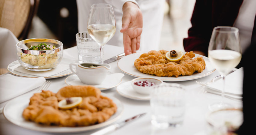 Where to eat schnitzel in Vienna. In the picture, a waiter serves a plate of schnitzel at Meissl & Schadn.