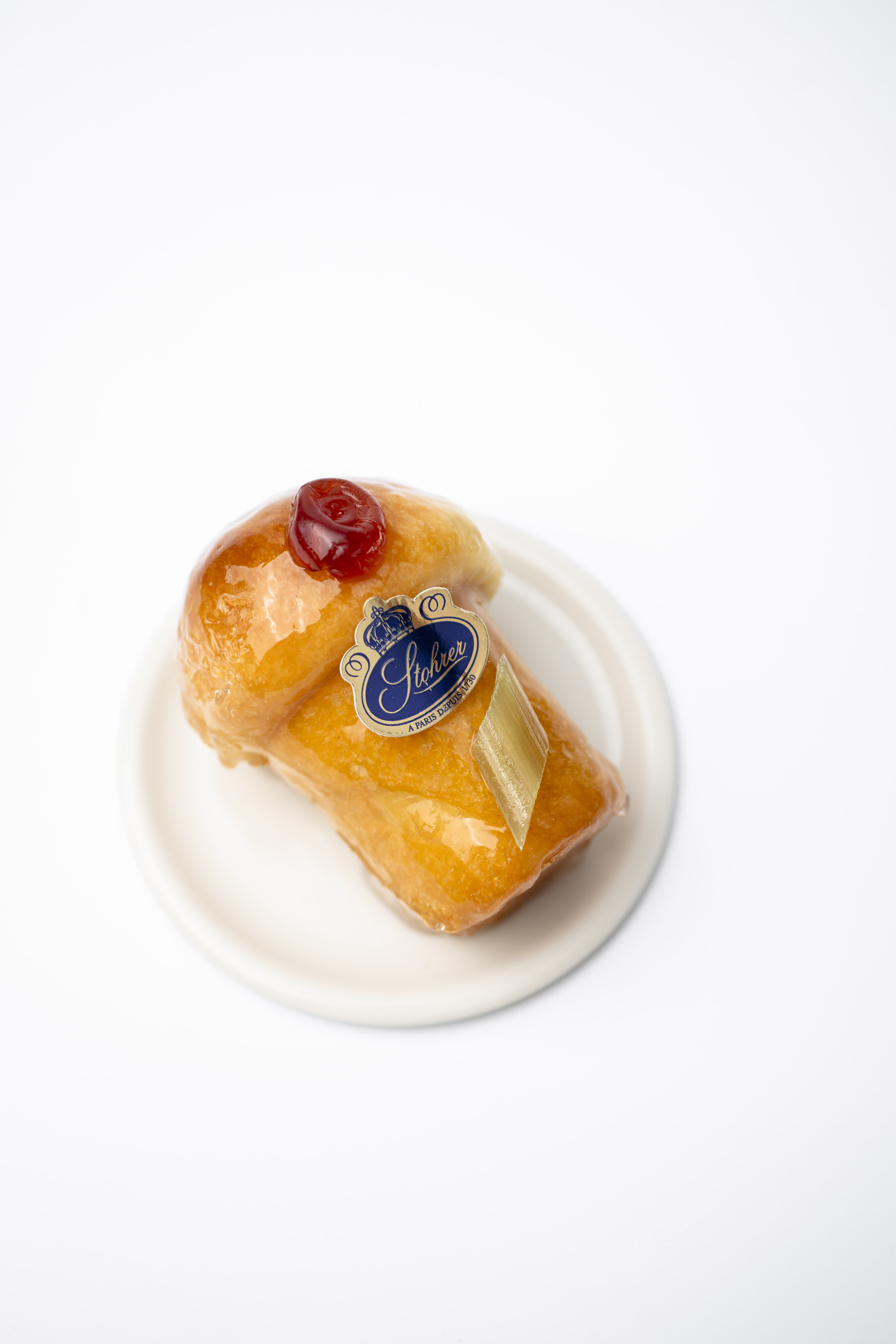 The best patisseries in Paris. Pictured here is a small cake covered in shiny transparent caramel, topped with candied fruit and the Stohrer emblem.
