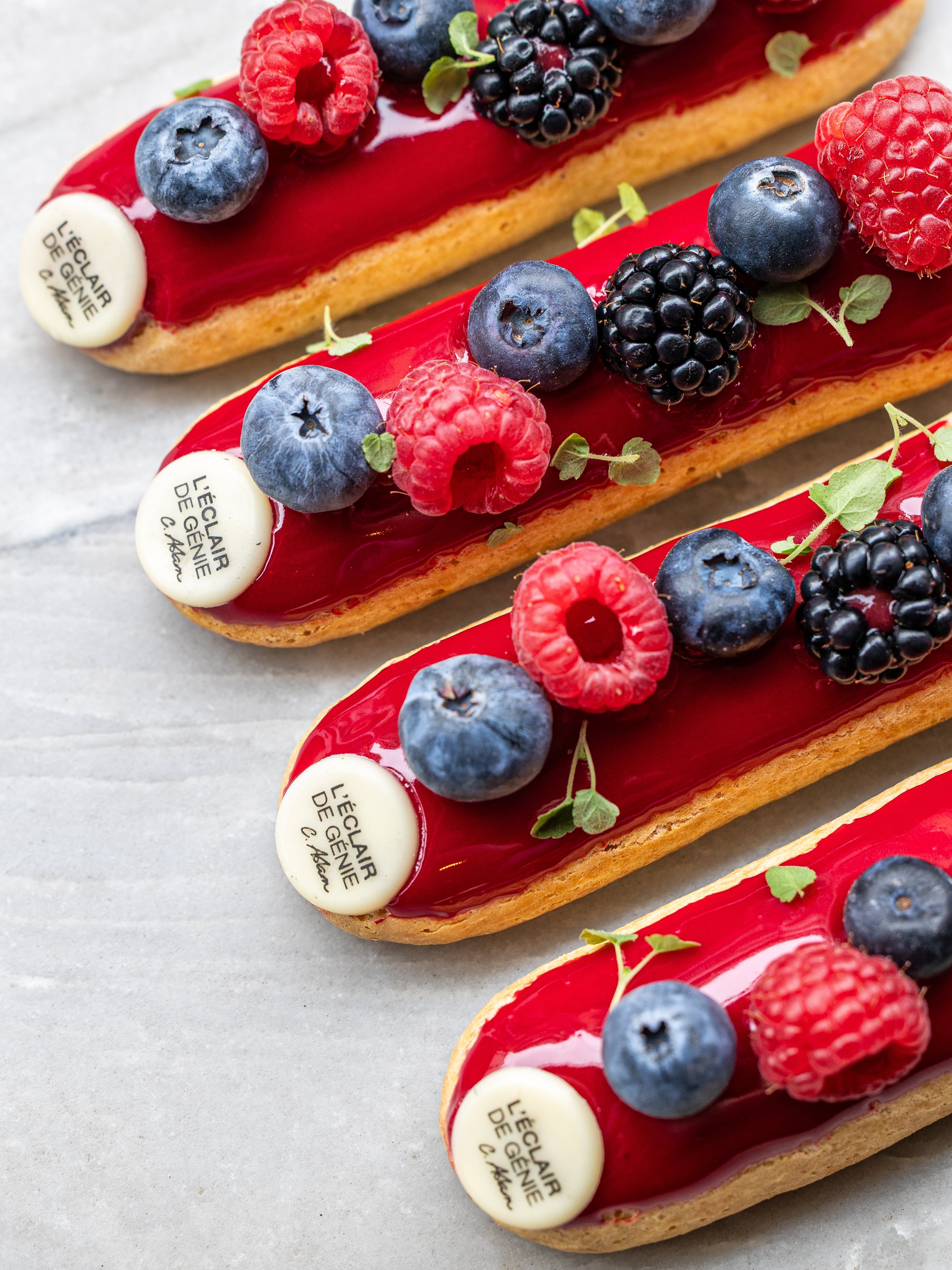 The best patisseries in Paris. Pictured here are éclairs covered in red cream and topped with berries and flower petals.