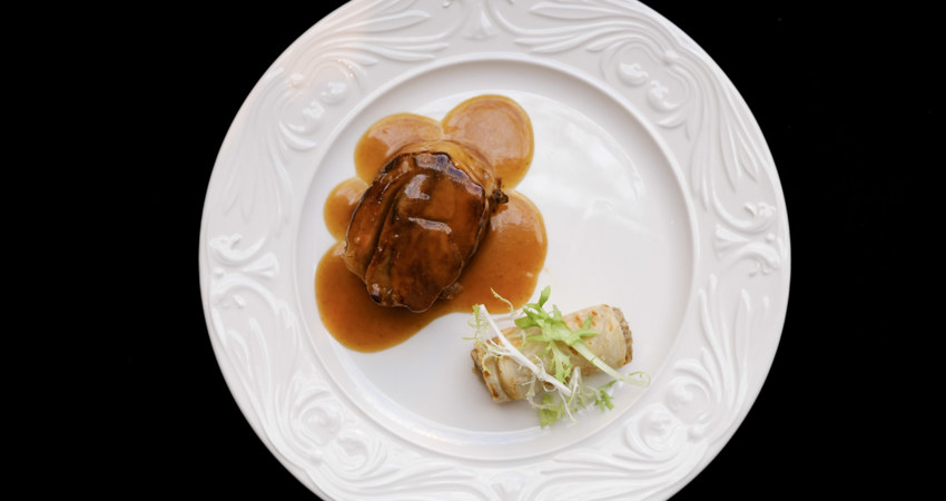En la imagen, uno de los platos de porcelana del Hotel Palace, sobre fondo negro. Solomillo en salsa con acompañamiento vegetal