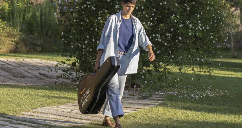 Entrevista a Alba Flores. En la image, Alba camina con una funda de guitarra de su padre, con el nombre de Antonio Flores bordado en el lateral
