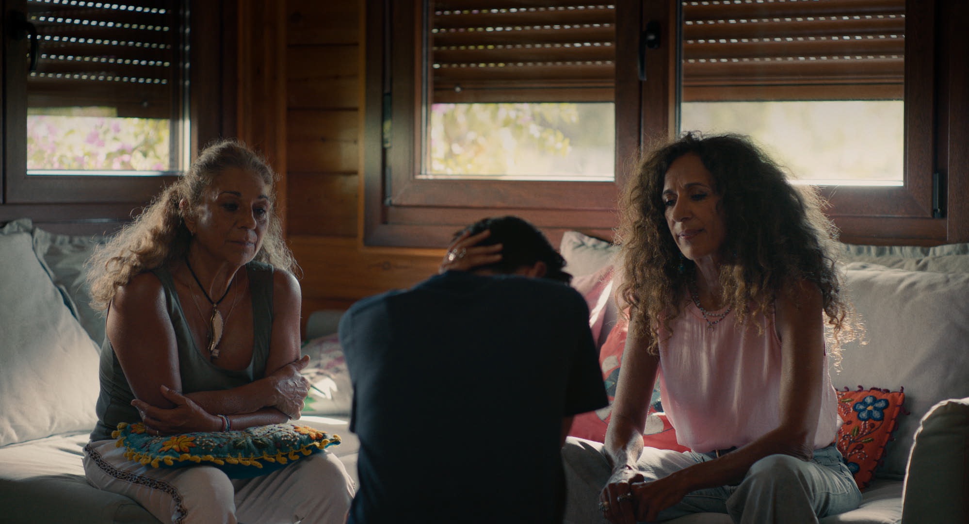 En la imagen, en una habitación en penumbra, Alba se sienta de espaldas a la cámara mientras sus tías Lolita y Rosario, de frente, la miran