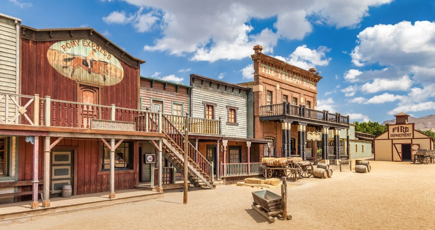 The image shows a Wild West setting with red wooden houses.