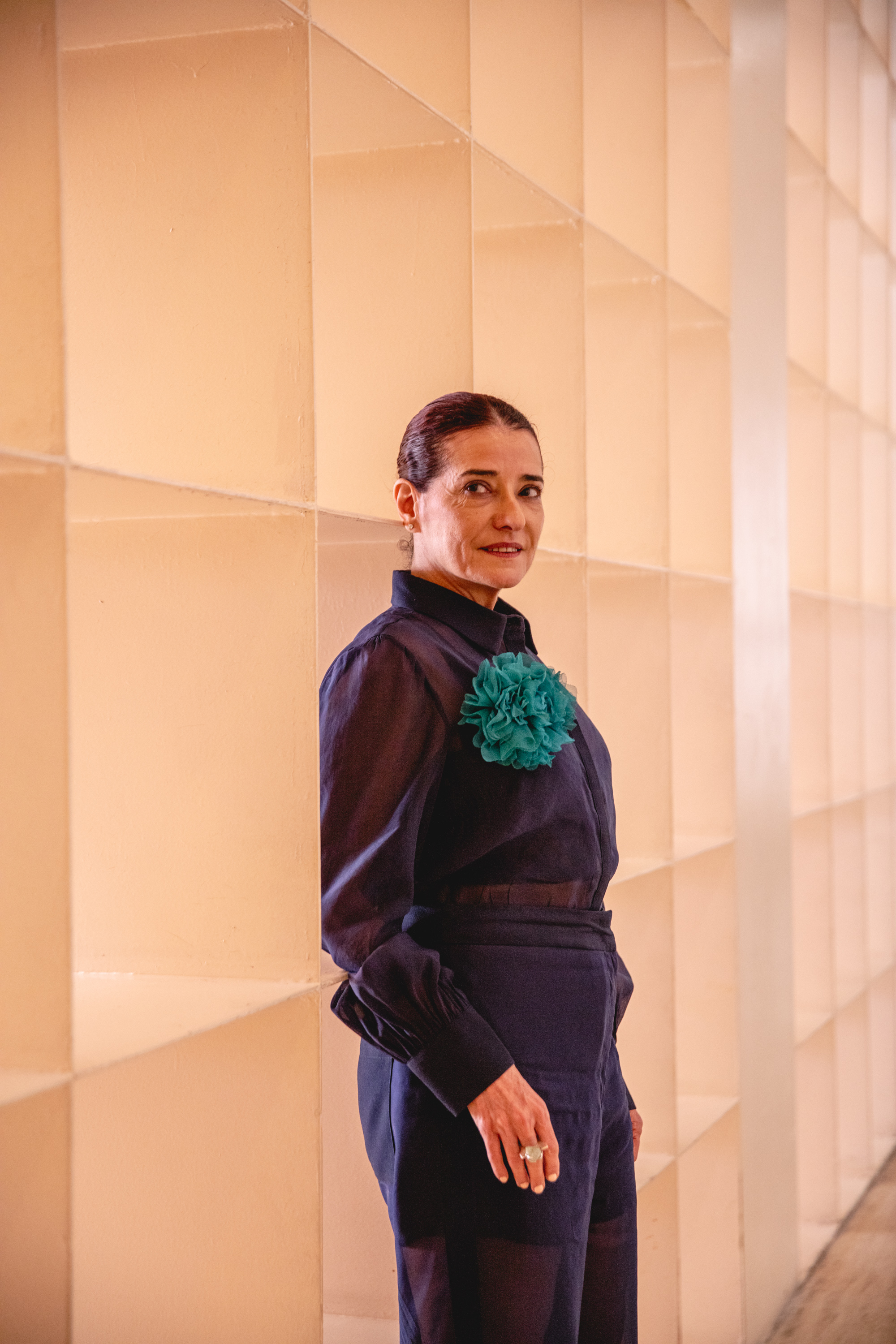 Taiyana Pimentel posa, ligeramente de perfil, en el Museo Marco, junto una pared de cubos que dejan pasar la luz. La direcotra lleva una camisa azul marino y un broche en forma de flor, hecha en gasa y de color aguamarina